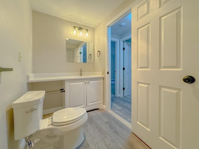 bathroom featuring toilet, vanity, and wood finished floors