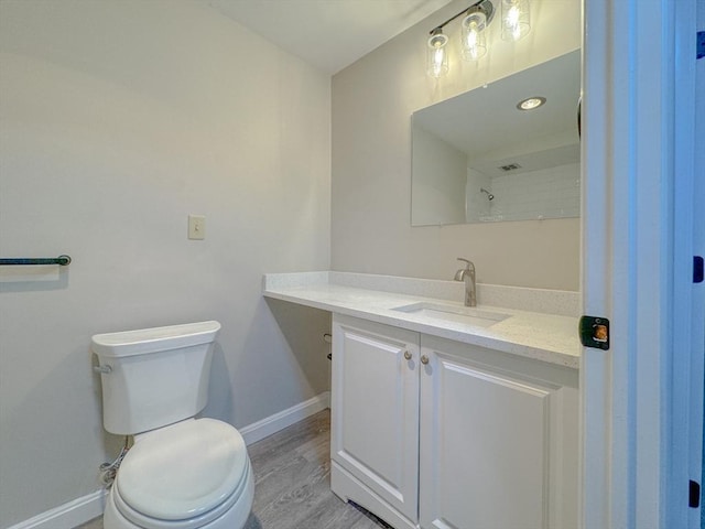 bathroom with baseboards, toilet, vanity, and wood finished floors