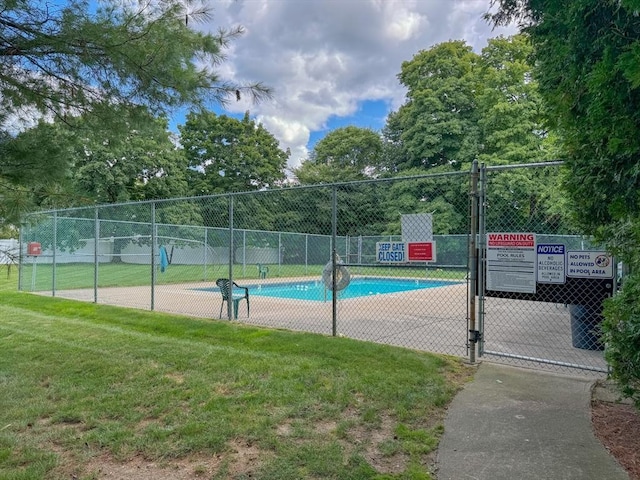 view of swimming pool with a lawn, a gate, and fence