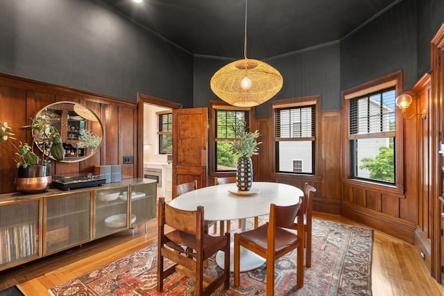332 Eliot St, Milton, MA 02186 - dining space with light wood finished floors, a high ceiling, wooden walls, and ornamental molding