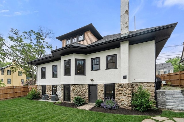 332 Eliot St, Milton, MA 02186 - back of house featuring stone siding, a fenced backyard, and stucco siding