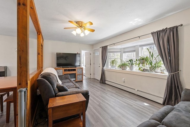 living area featuring ceiling fan, a baseboard heating unit, and wood finished floors