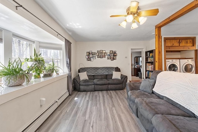 living area with separate washer and dryer, ceiling fan, a baseboard heating unit, and light wood-style floors
