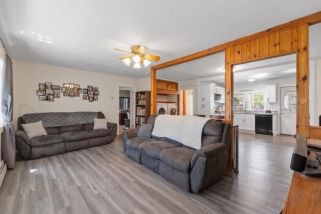 living room featuring separate washer and dryer, ceiling fan, and wood finished floors