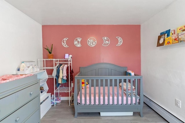 bedroom featuring baseboard heating and wood finished floors