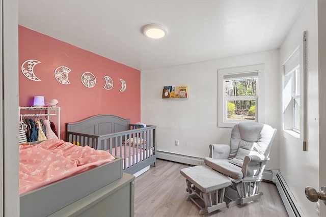 bedroom featuring baseboards, a baseboard heating unit, and light wood-style flooring