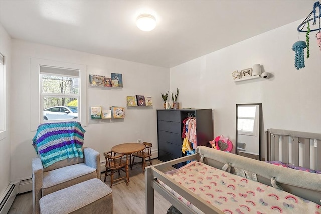 bedroom featuring a baseboard radiator, light wood-style flooring, and multiple windows