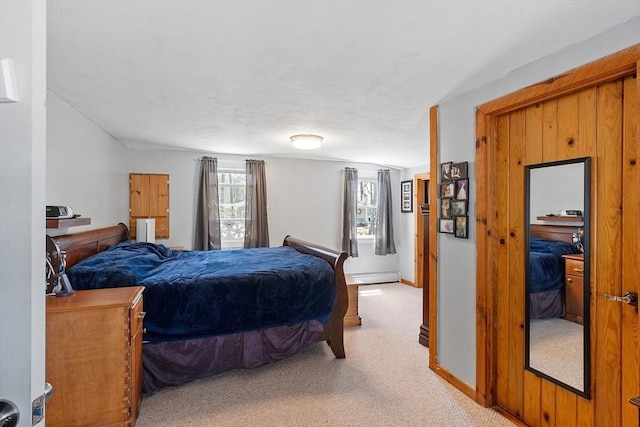 bedroom featuring light colored carpet, baseboards, and a baseboard heating unit