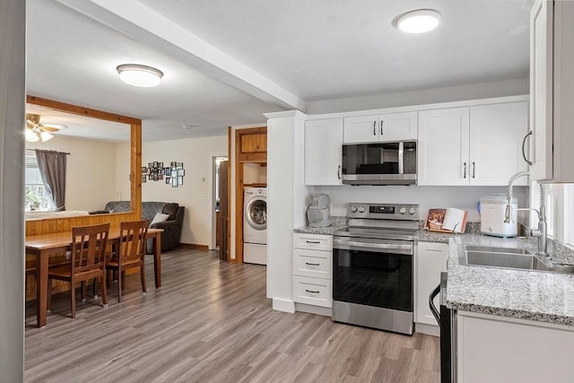 kitchen with washer / clothes dryer, light stone counters, white cabinets, stainless steel appliances, and light wood-style flooring