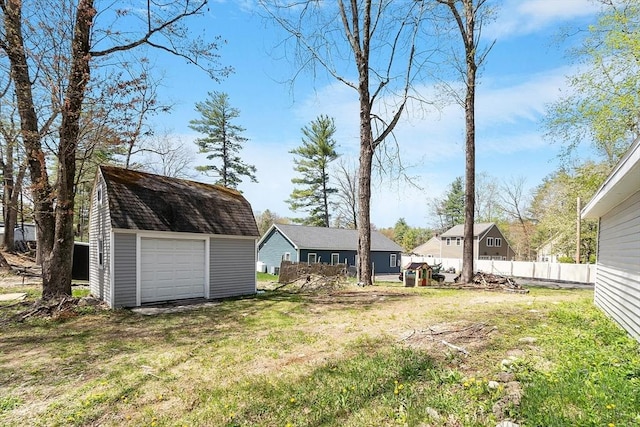 view of yard featuring a garage, fence, and an outbuilding