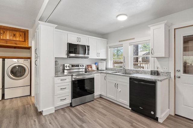 kitchen featuring light wood-style floors, appliances with stainless steel finishes, a sink, white cabinets, and washer / dryer