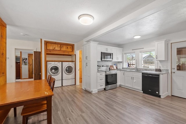 kitchen featuring washing machine and clothes dryer, stainless steel appliances, white cabinetry, and light wood finished floors