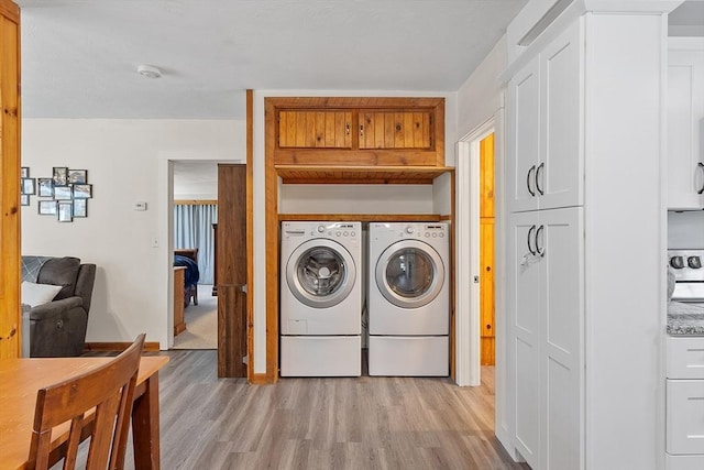 washroom with cabinet space, separate washer and dryer, and light wood finished floors