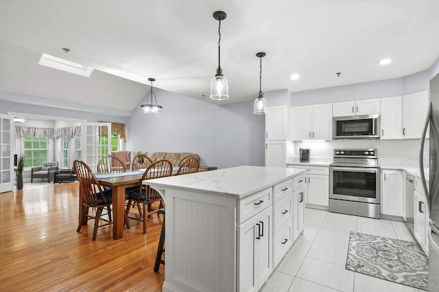 179 Hillside Village Dr Unit 179, West Boylston, MA 01583 - kitchen with appliances with stainless steel finishes, a center island, white cabinets, light stone countertops, and decorative light fixtures