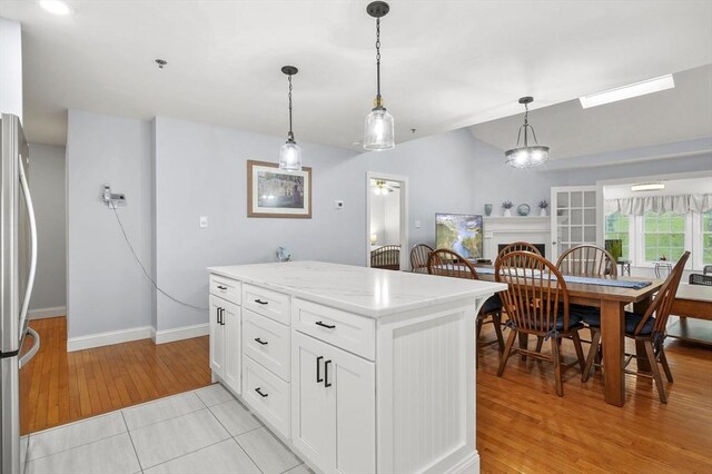179 Hillside Village Dr Unit 179, West Boylston, MA 01583 - kitchen featuring baseboards, light wood-type flooring, freestanding refrigerator, pendant lighting, and white cabinets