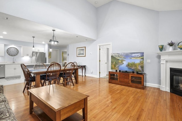 179 Hillside Village Dr Unit 179, West Boylston, MA 01583 - living room featuring light wood-type flooring, a glass covered fireplace, recessed lighting, baseboards, and a towering ceiling