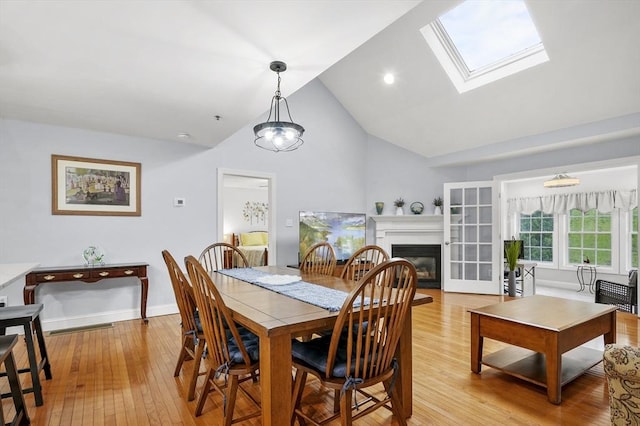 179 Hillside Village Dr Unit 179, West Boylston, MA 01583 - dining room featuring light wood-style flooring, a glass covered fireplace, high vaulted ceiling, a skylight, and baseboards
