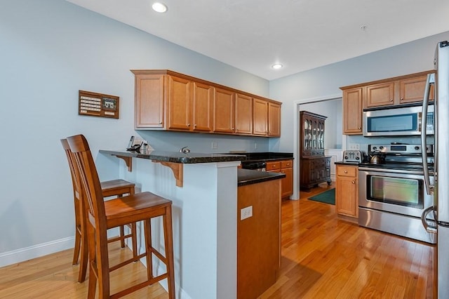 17 Cortland Grove Dr Unit 17, Shrewsbury, MA 01545 - kitchen with appliances with stainless steel finishes, a peninsula, light wood finished floors, a kitchen breakfast bar, and recessed lighting
