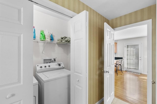 clothes washing area with laundry area, washer / clothes dryer, light wood-style floors, and wallpapered walls