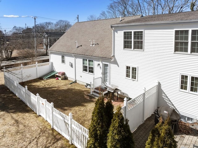 back of property with entry steps, a patio, a fenced backyard, roof with shingles, and a lawn