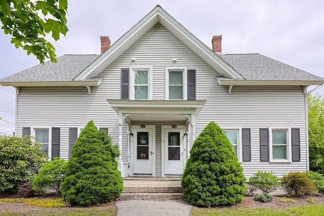 view of front of home featuring a chimney and roof with shingles