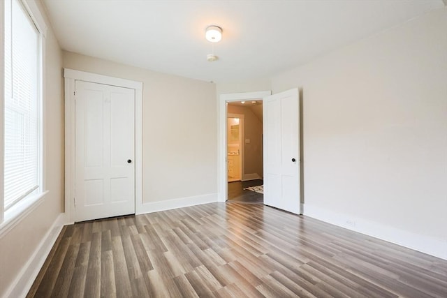 unfurnished bedroom featuring wood finished floors, baseboards, and a closet