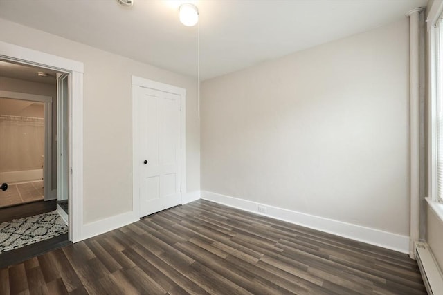 unfurnished bedroom featuring dark wood-type flooring, baseboards, a baseboard radiator, and a closet