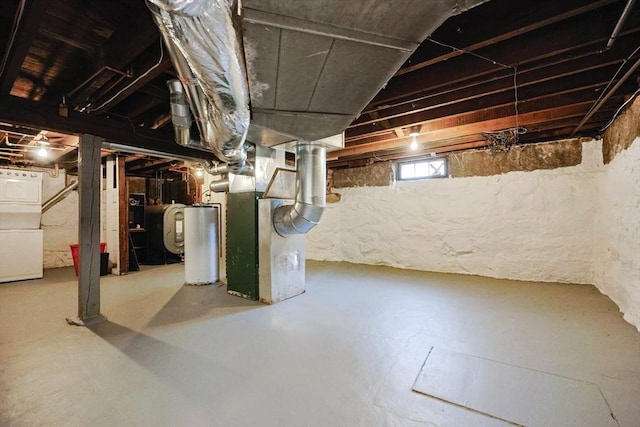 below grade area featuring water heater, heating unit, and washer / dryer