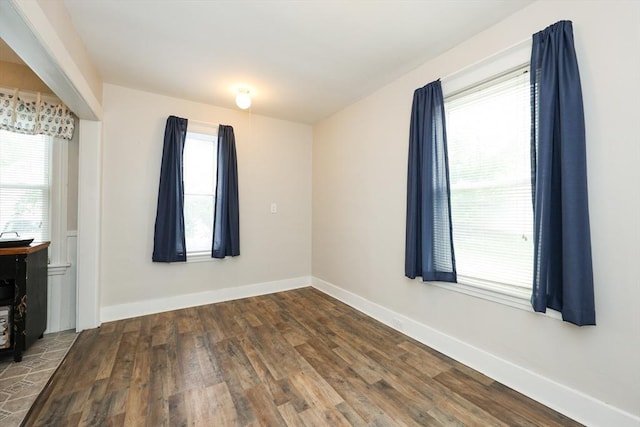 unfurnished room featuring wood finished floors, healthy amount of natural light, and baseboards
