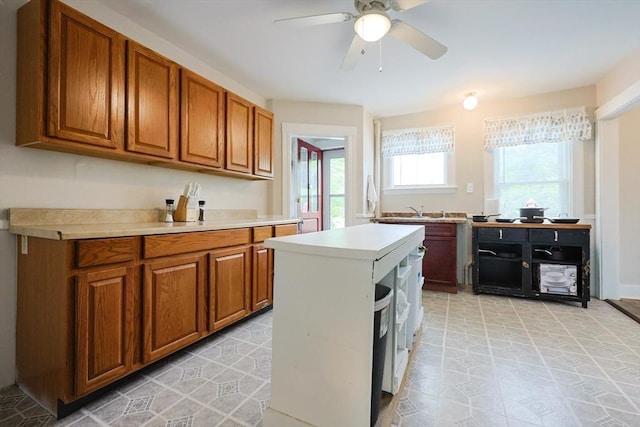 kitchen featuring brown cabinets, light countertops, a ceiling fan, and a sink