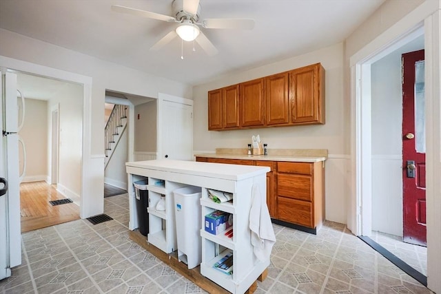 kitchen with open shelves, brown cabinetry, light countertops, a ceiling fan, and freestanding refrigerator
