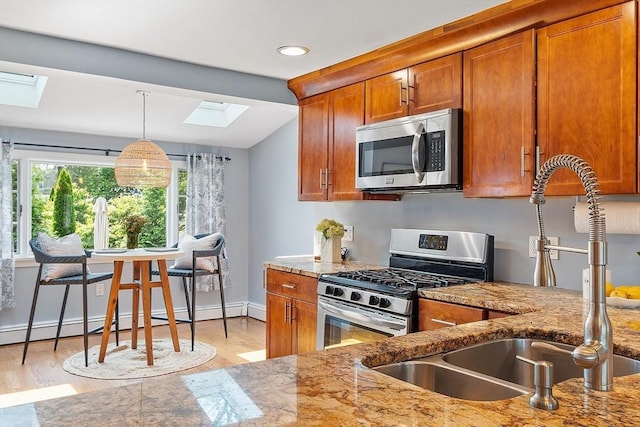 9 Crescent Ave, Lynnfield, MA 01940 - kitchen with stainless steel appliances, a skylight, brown cabinets, a baseboard heating unit, and light wood-style floors