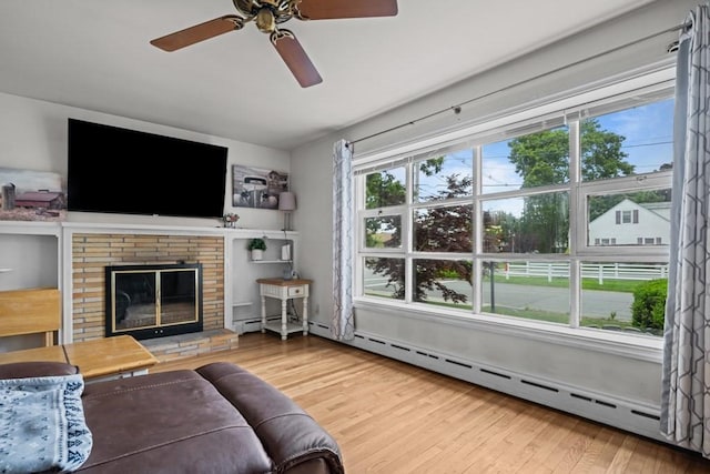 34 Coolidge St, Dartmouth, MA 02748 - living room with wood finished floors, a ceiling fan, a baseboard radiator, and a fireplace