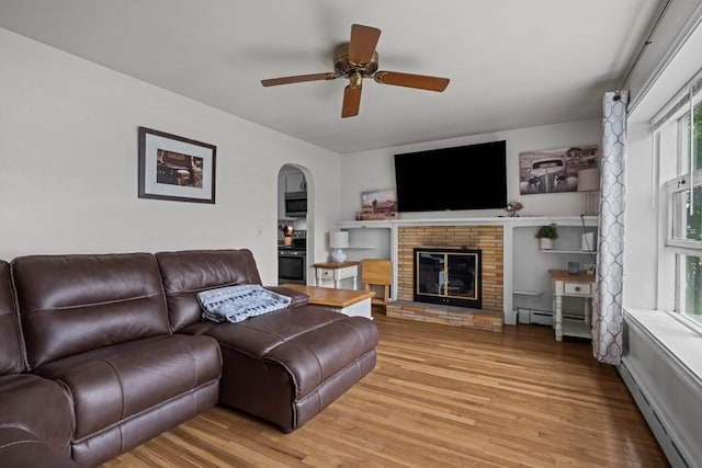 34 Coolidge St, Dartmouth, MA 02748 - living area featuring light wood finished floors, a ceiling fan, arched walkways, baseboard heating, and a fireplace