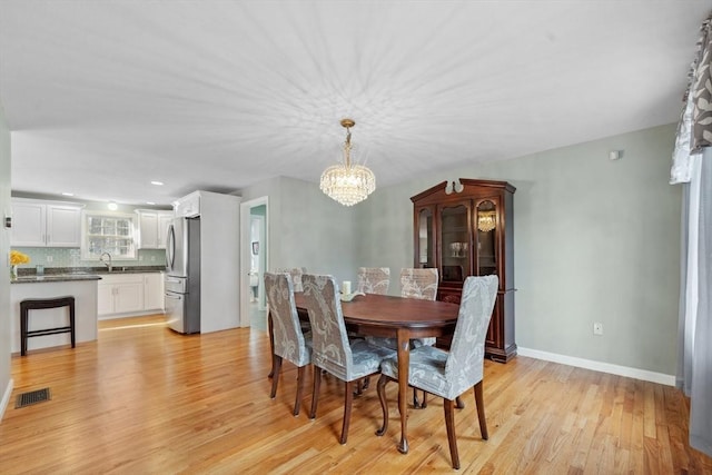 dining area featuring light hardwood / wood-style flooring, a chandelier, and sink