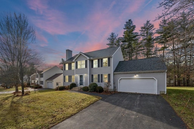 colonial-style house featuring a lawn and a garage