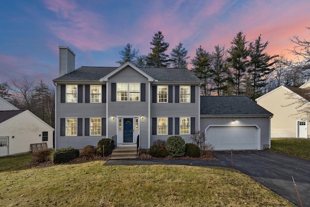 colonial house featuring a yard and a garage