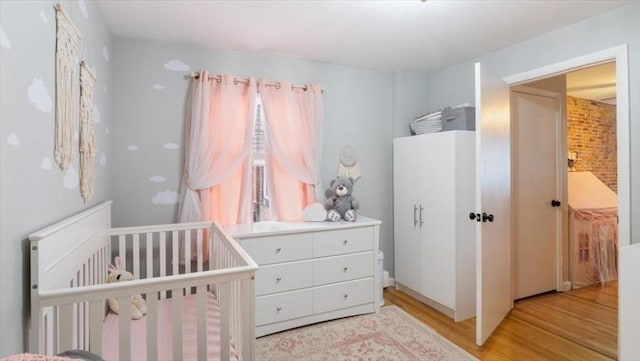 bedroom with a nursery area and light wood-type flooring