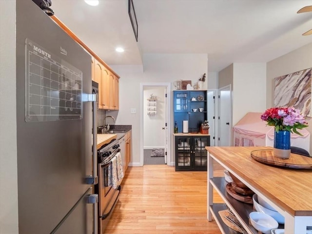 kitchen featuring light brown cabinets, a sink, light wood-style floors, appliances with stainless steel finishes, and open shelves