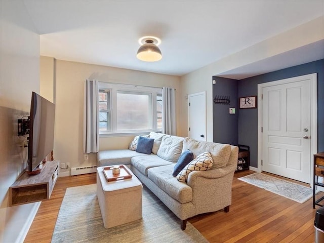 living area featuring light wood-style flooring, a baseboard heating unit, and baseboards