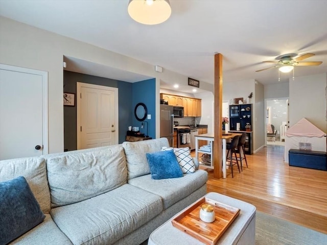 living room featuring baseboards, light wood-style flooring, and a ceiling fan