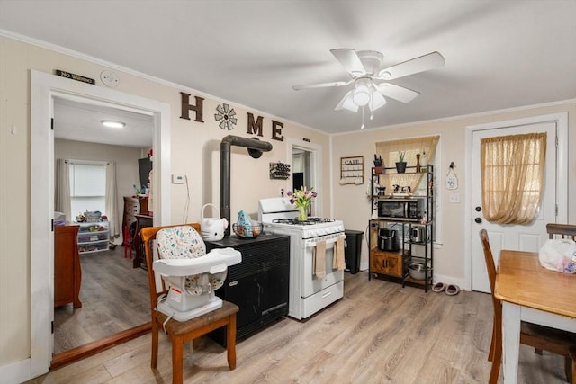 kitchen with stainless steel microwave, light wood-style flooring, white gas stove, and ceiling fan