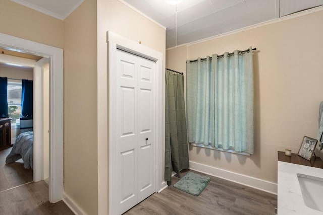 bathroom featuring ornamental molding, a shower with shower curtain, baseboards, and wood finished floors