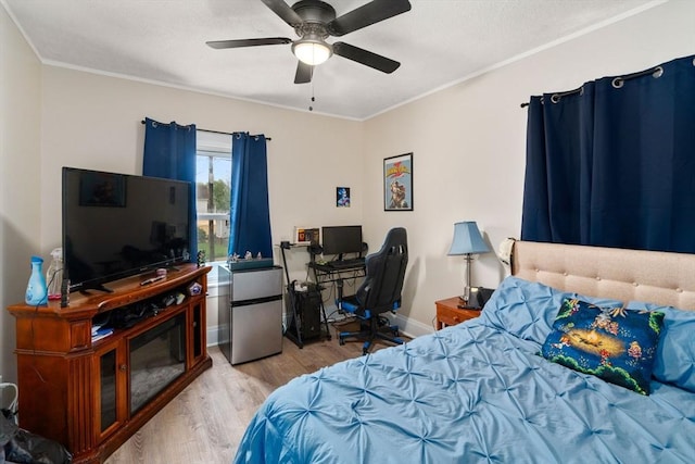bedroom with freestanding refrigerator, crown molding, a ceiling fan, and wood finished floors