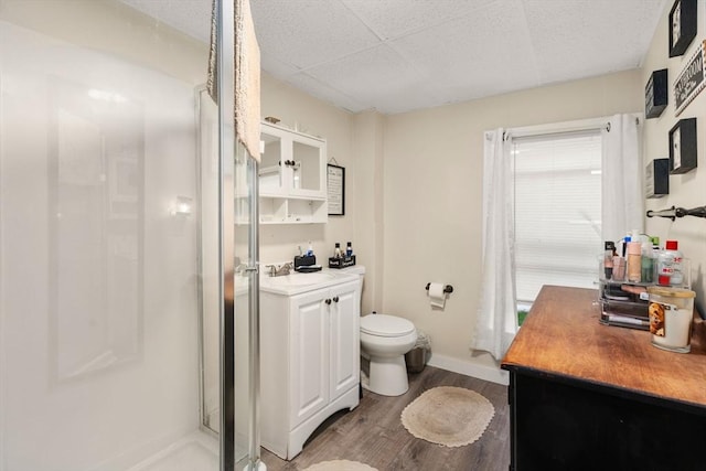 full bath featuring toilet, wood finished floors, vanity, a shower stall, and baseboards