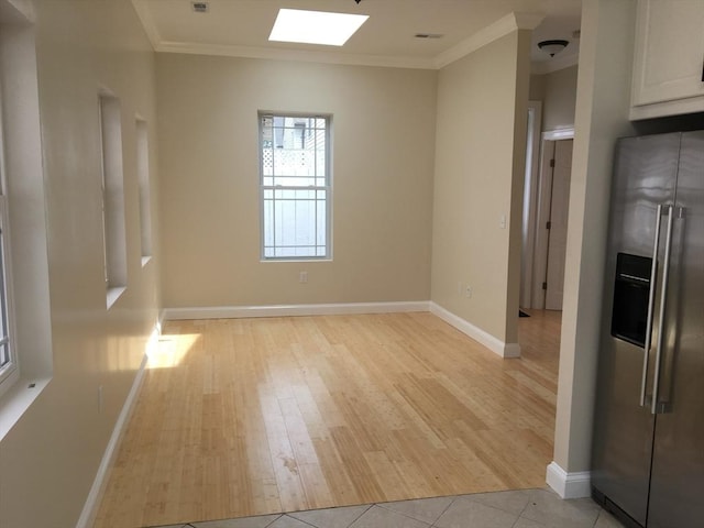 interior space with light tile patterned floors, a skylight, and ornamental molding