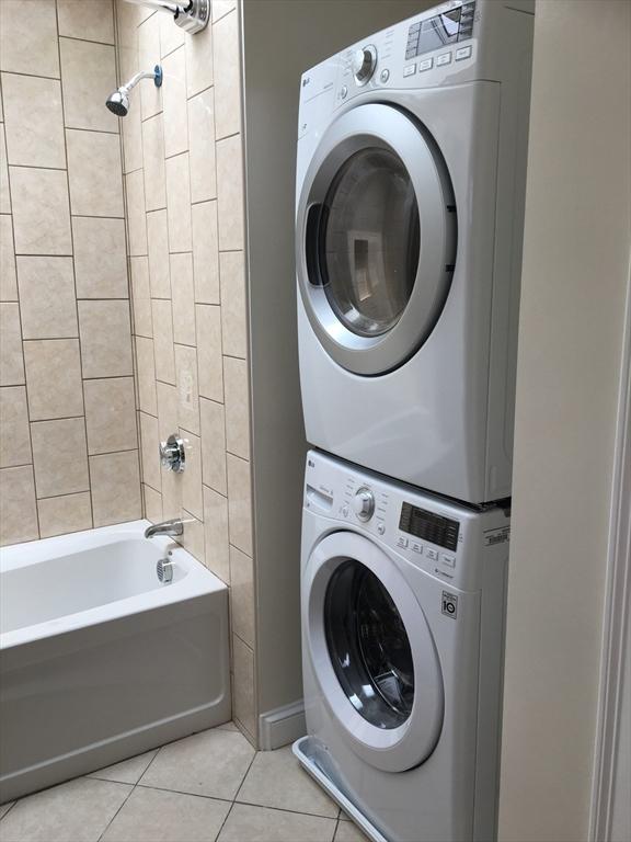 laundry area with stacked washer / dryer and light tile patterned floors