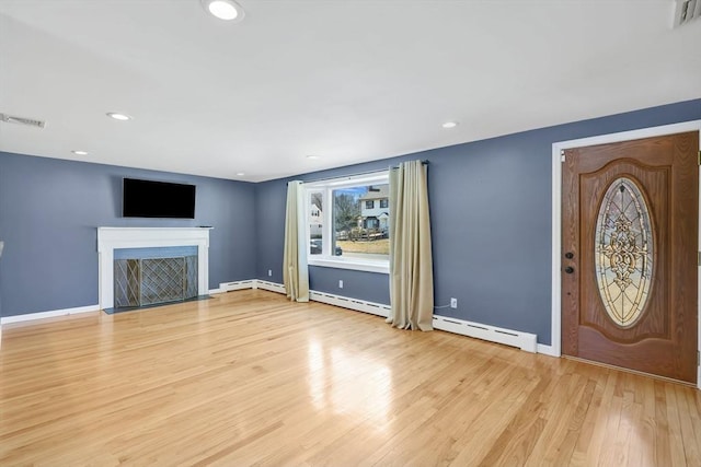 unfurnished living room with visible vents, baseboards, a fireplace with flush hearth, light wood-style floors, and a baseboard radiator