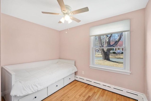 unfurnished bedroom featuring a baseboard heating unit, light wood finished floors, and ceiling fan