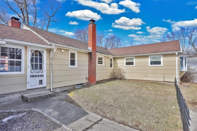 back of property featuring a yard, a shingled roof, a chimney, and entry steps